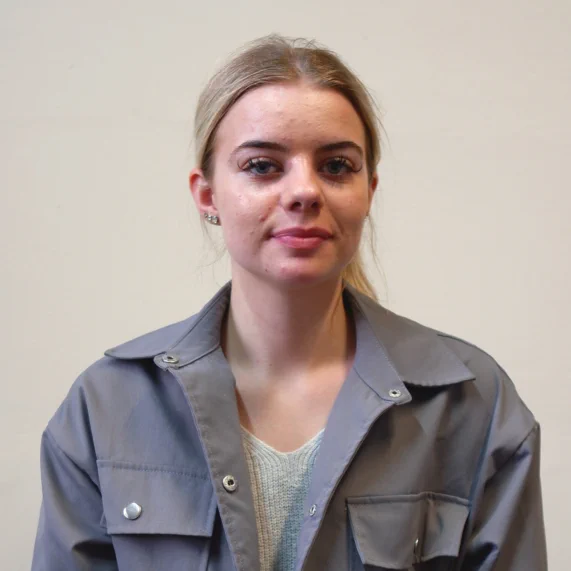 Team member - A lady in a grey buttoned coat with blonde hair, smiling